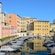 A water canal lined with docked boats runs past vibrant multi story buildings